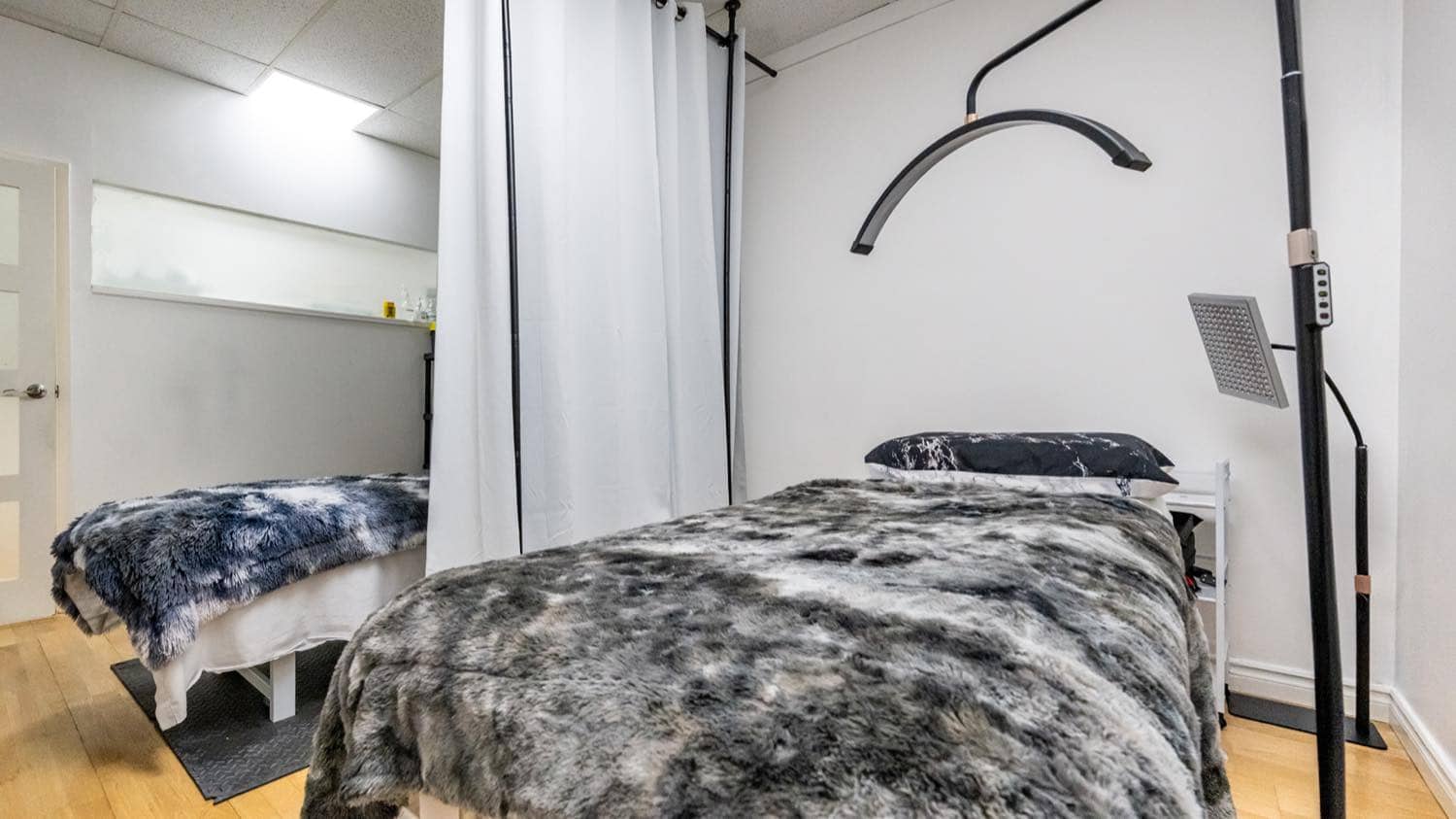 A treatment room set up for facials and skin treatments, with a curtained bay and an adjustable lamp