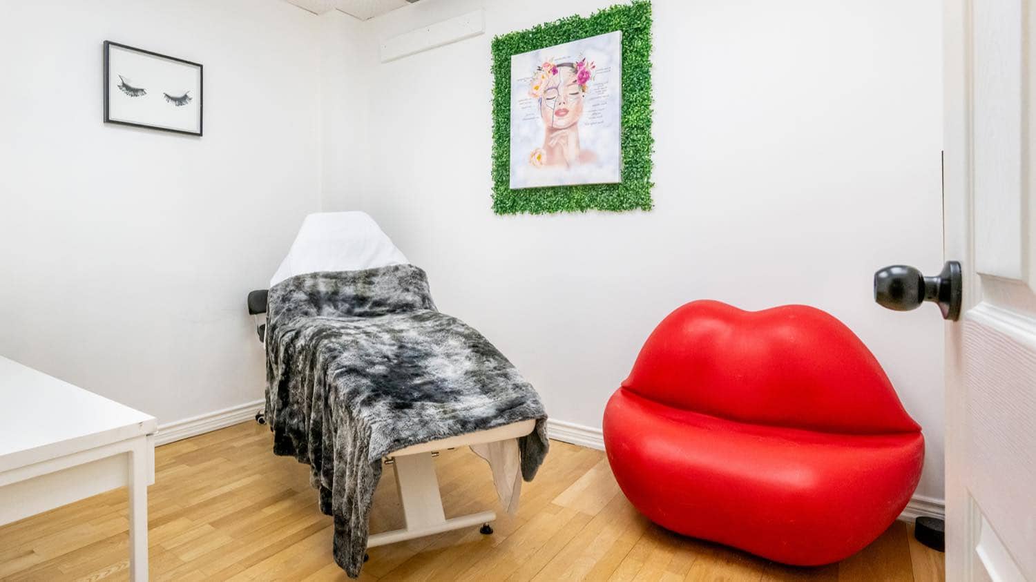 The lash and beauty room at iBODY, with a treatment bed and a red lip-shaped chair