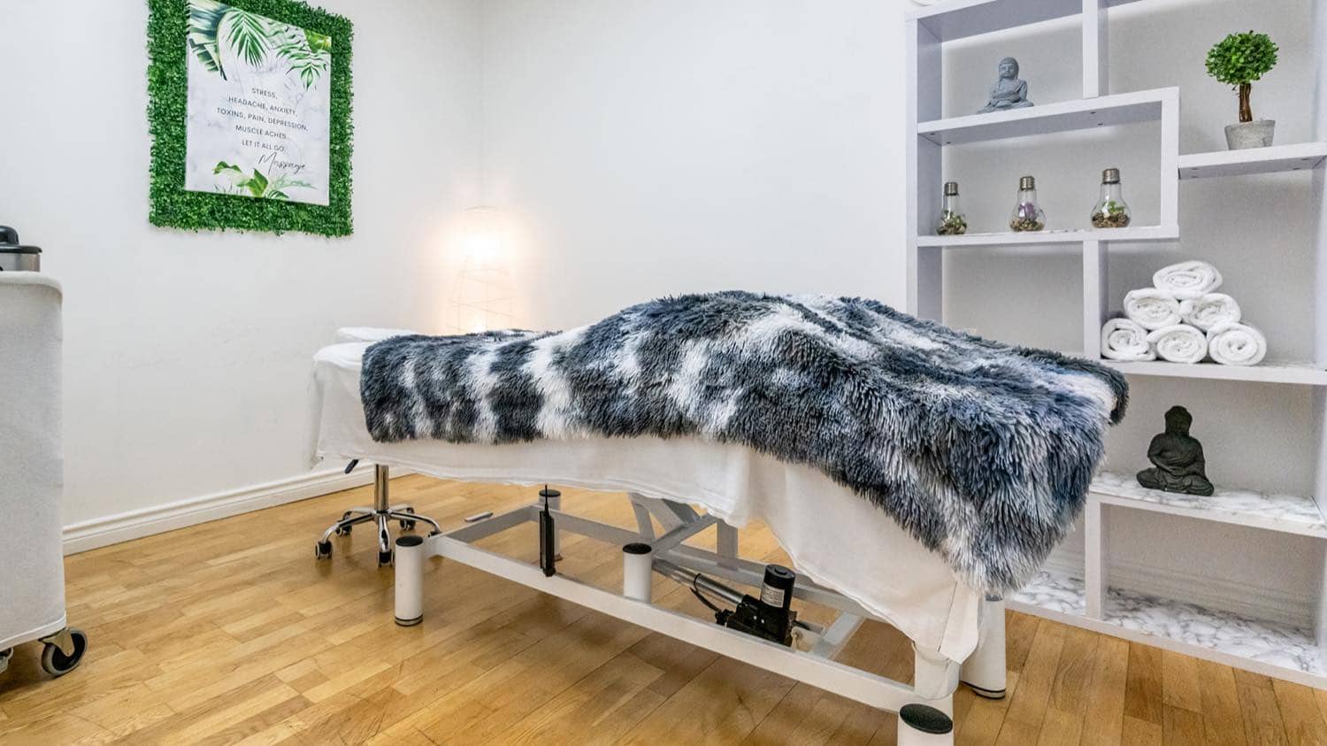 A massage therapy room at iBODY, with a treatment table and open shelving